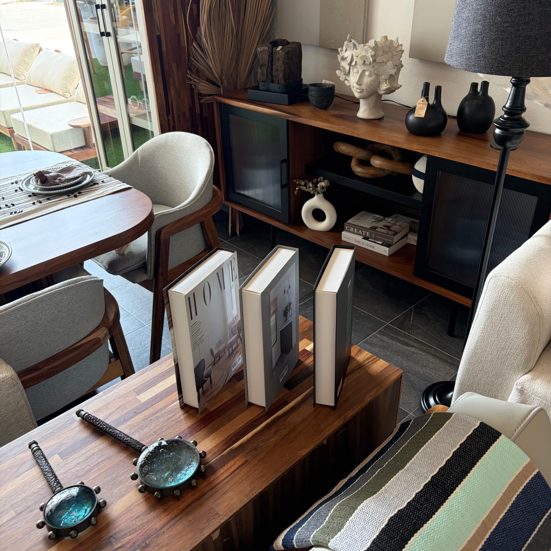 Rincón del showroom con comedor de parota, libros de diseño y objetos de autor, Mezquite Los Cabos
